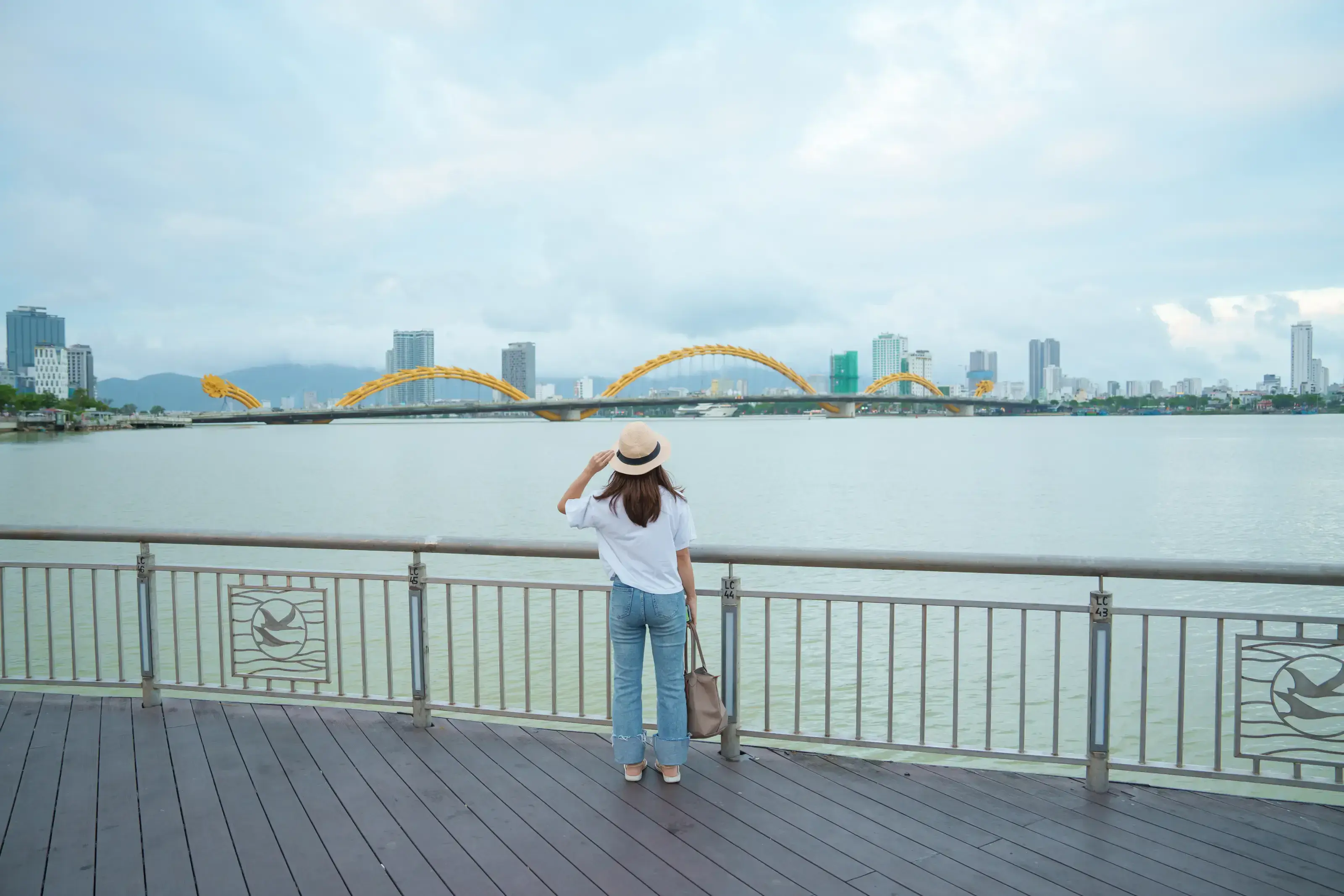 Woman Traveler visiting in Da Nang city. Tourist sightseeing the river view with Dragon bridge. Landmark and popular for tourist attraction. Vietnam and Southeast Asia